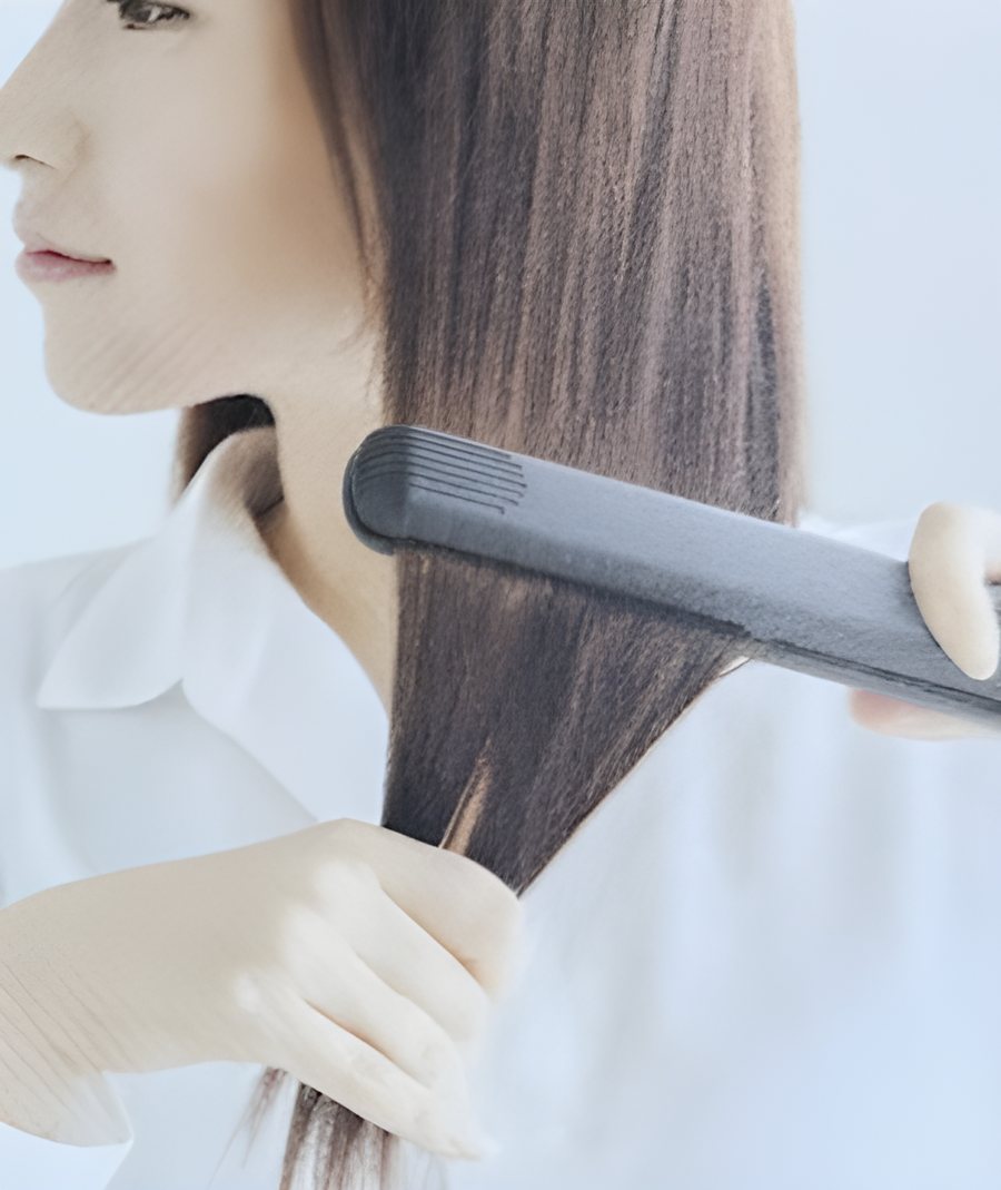 髪をヘアアイロンで仕上げる女性